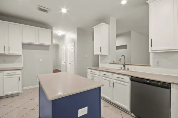 a kitchen with a sink dishwasher a stove and white cabinets