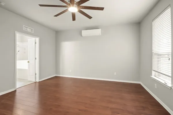 an empty room with wooden floor closet and windows