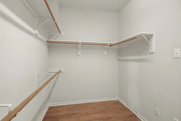 an empty room with wooden floor cabinet and windows