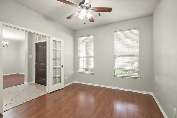 a view of an empty room with wooden floor and a window
