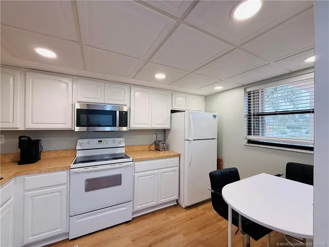 a kitchen with a sink a white cabinets and white appliances