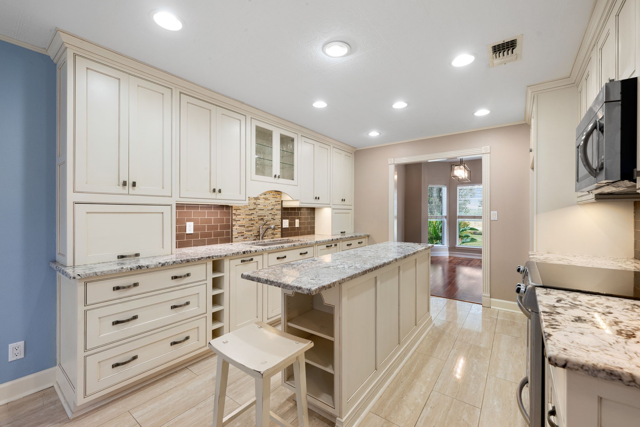 17207 Penick Road Waller, TX 77484 - Photo 14 of 37 This kitchen features neutral-toned cabinetry and a central island with storage and seating for the chef to prepare meals. It has modern stainless steel appliances, ample storage, and recessed lighting, creating a bright and inviting cooking space.