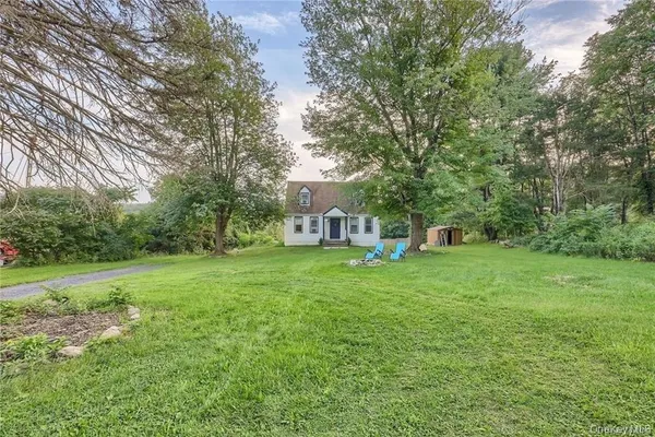 a view of a house with a yard and a large tree