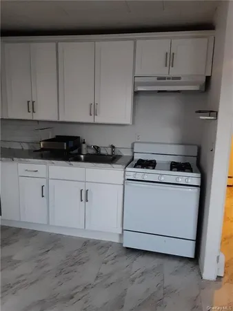 a kitchen with granite countertop white cabinets and a stove