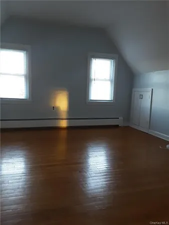 an empty room with wooden floor and windows with curtains
