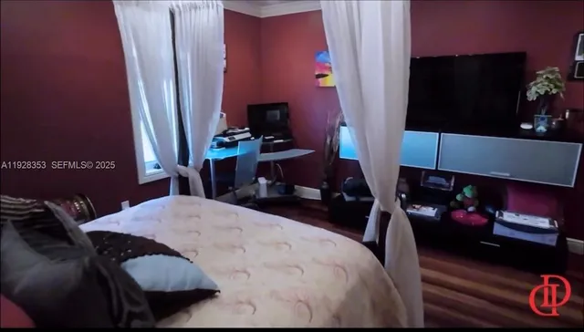 a bedroom with a bed a flat screen tv and a potted plant