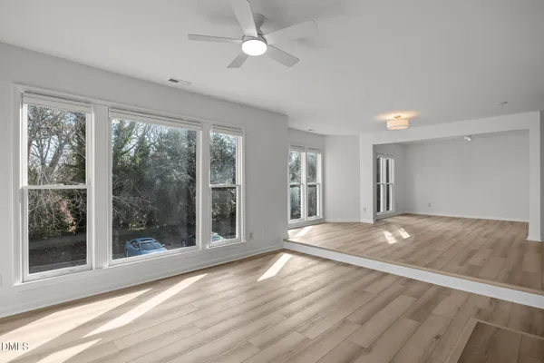 a view of empty room with wooden floor and fan