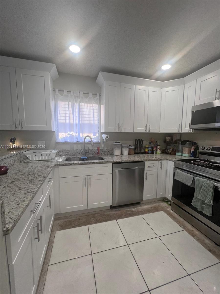 4681 Cherry Road West Palm Beach, FL 33417 - Photo 9 of 33 a kitchen with a sink a stove a microwave and cabinets