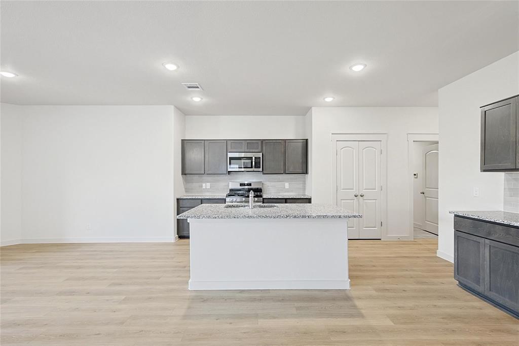 1759 Gleasondale Place Forney, TX 75126 - Photo 2 of 25 a large kitchen with stainless steel appliances a large counter top a stove a refrigerator and white cabinets
