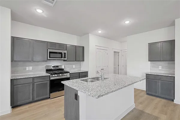 a kitchen with stainless steel appliances granite countertop a stove top oven a sink and dishwasher a refrigerator with wooden floor