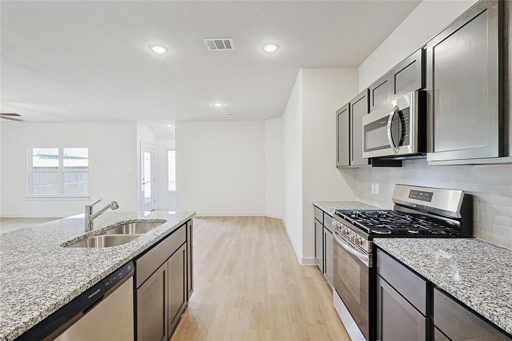 1759 Gleasondale Place Forney, TX 75126 - Photo 24 of 25 a kitchen with stainless steel appliances granite countertop a sink stove and cabinets