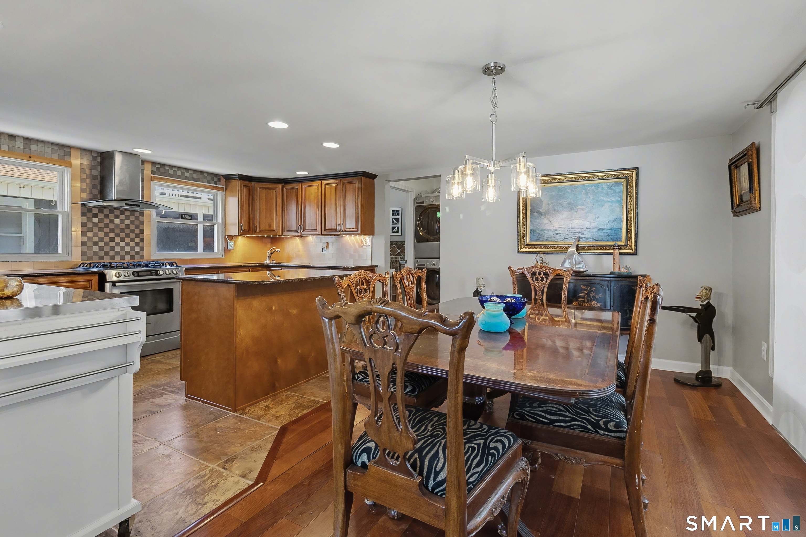 51 Point Beach Drive Milford, CT 06460 - Photo 11 of 32 a kitchen with stainless steel appliances granite countertop a stove top oven a refrigerator a dining table and chairs with wooden floor