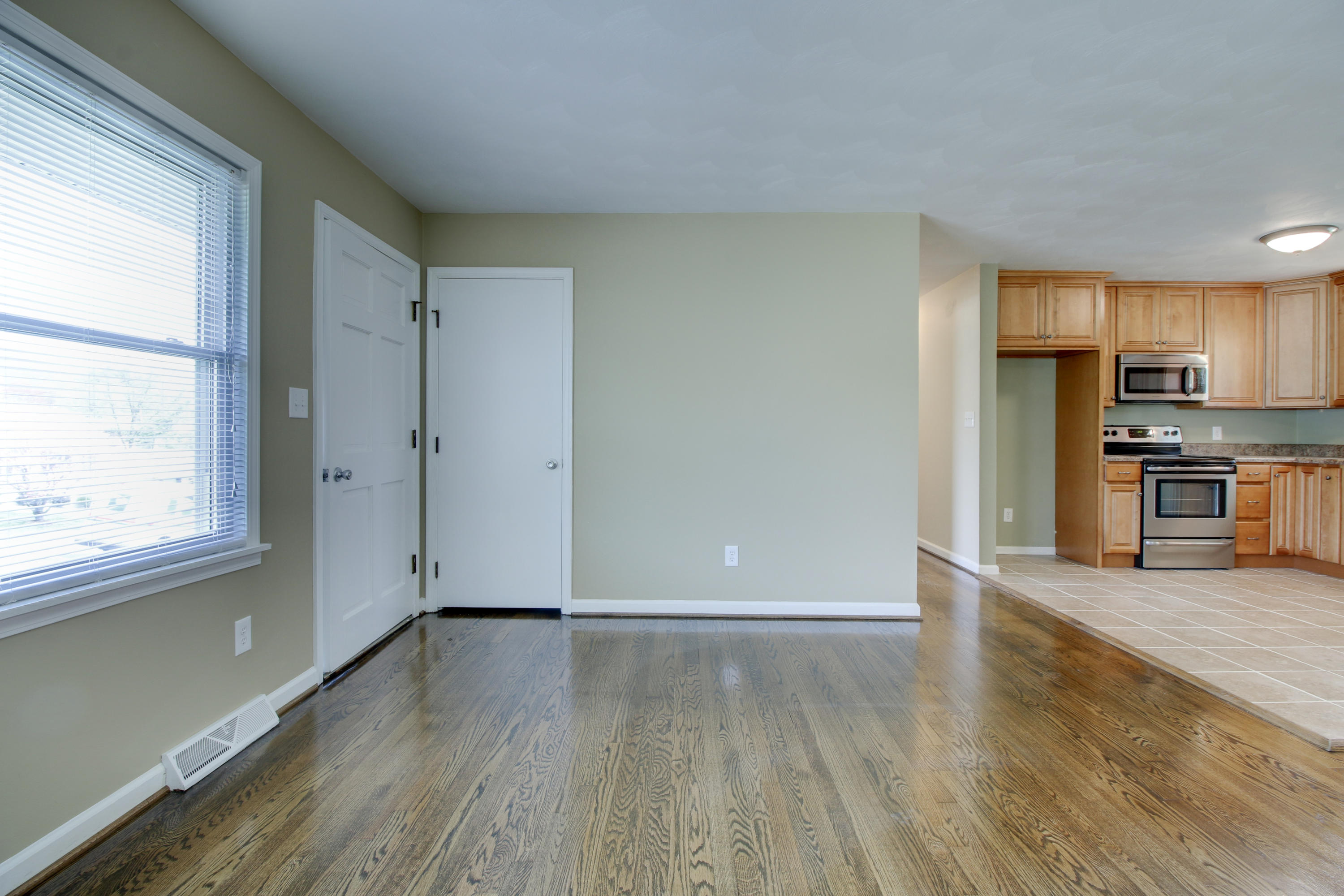 540 Olney Road Vinton, VA 24179 - Photo 4 of 29 an empty room with wooden floor and a kitchen