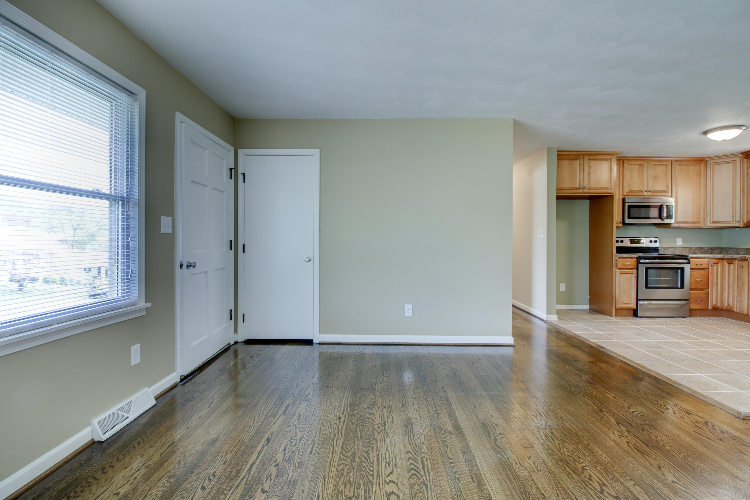 540 Olney Road Vinton, VA 24179 - Photo 5 of 29 an empty room with wooden floor and a kitchen