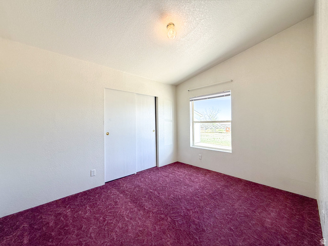141 South 100 East Emery, UT 84522 - Photo 10 of 17 Bedroom featuring a vaulted ceiling with a flush-mount light fixture, white walls, and purple patterned carpeting