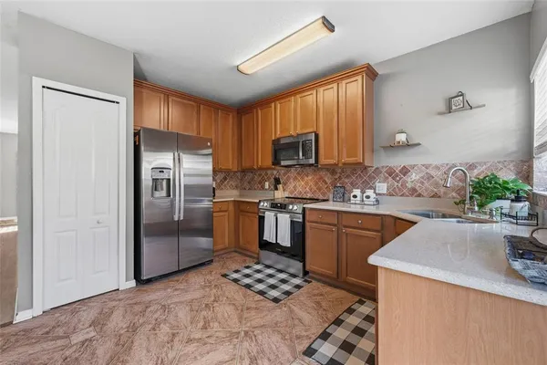 a kitchen with granite countertop stainless steel appliances a sink stove refrigerator and cabinets