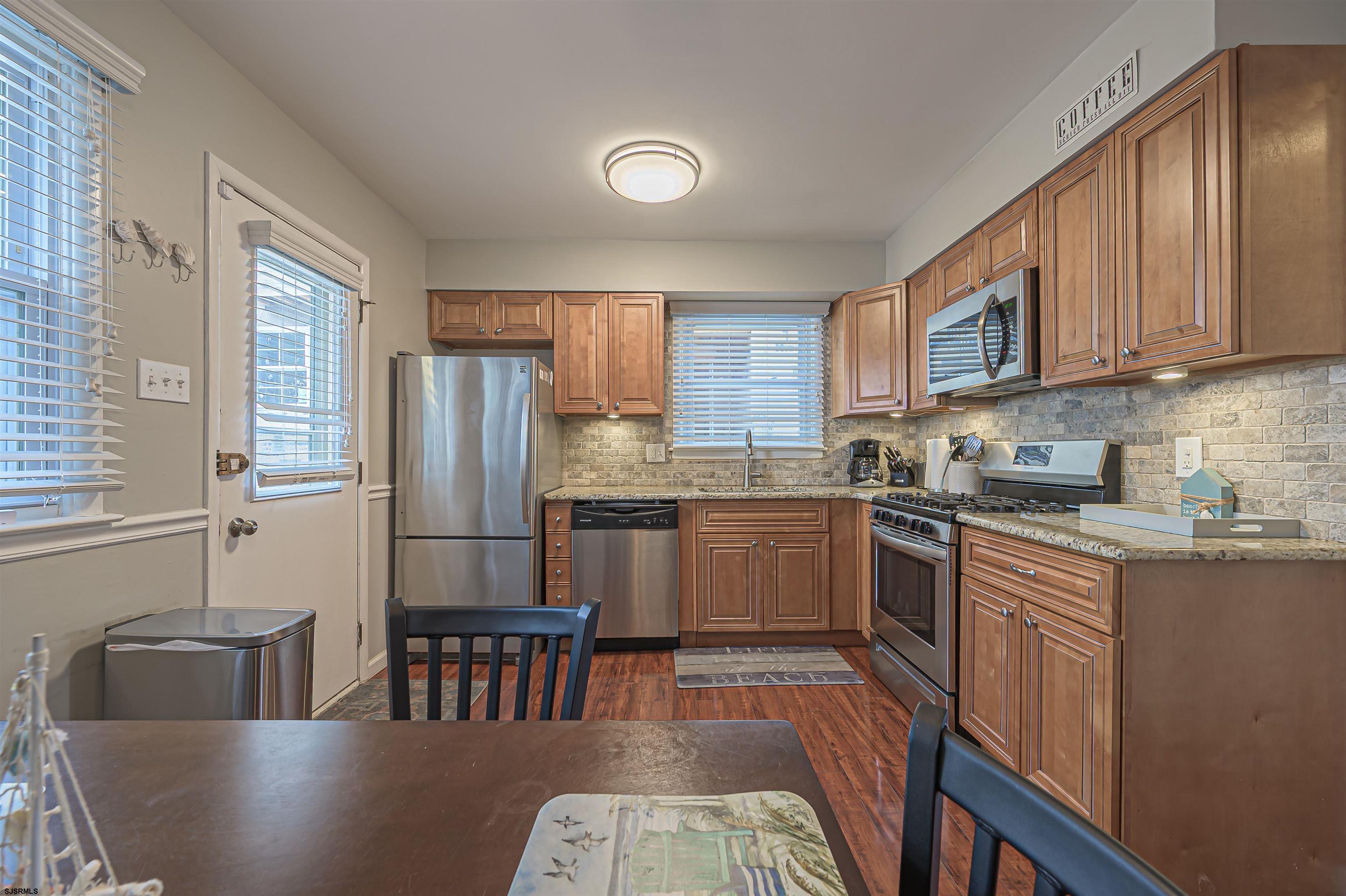 138 44th Street South, Unit D Brigantine, NJ 08203 - Photo 9 of 25 a kitchen with granite countertop a refrigerator a sink a stove a dining table and chairs
