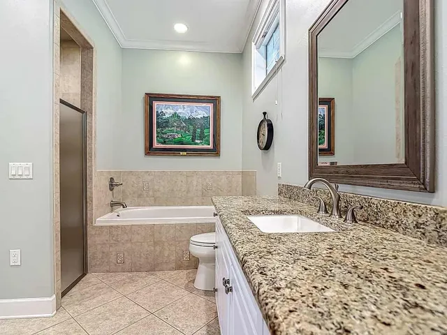 a bathroom with a granite countertop bathtub a sink and a mirror