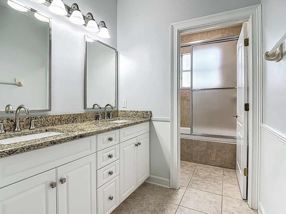 7330 36th Court Vero Beach, FL 32967 - Photo 20 of 33 a bathroom with a granite countertop sink two mirror and a shower