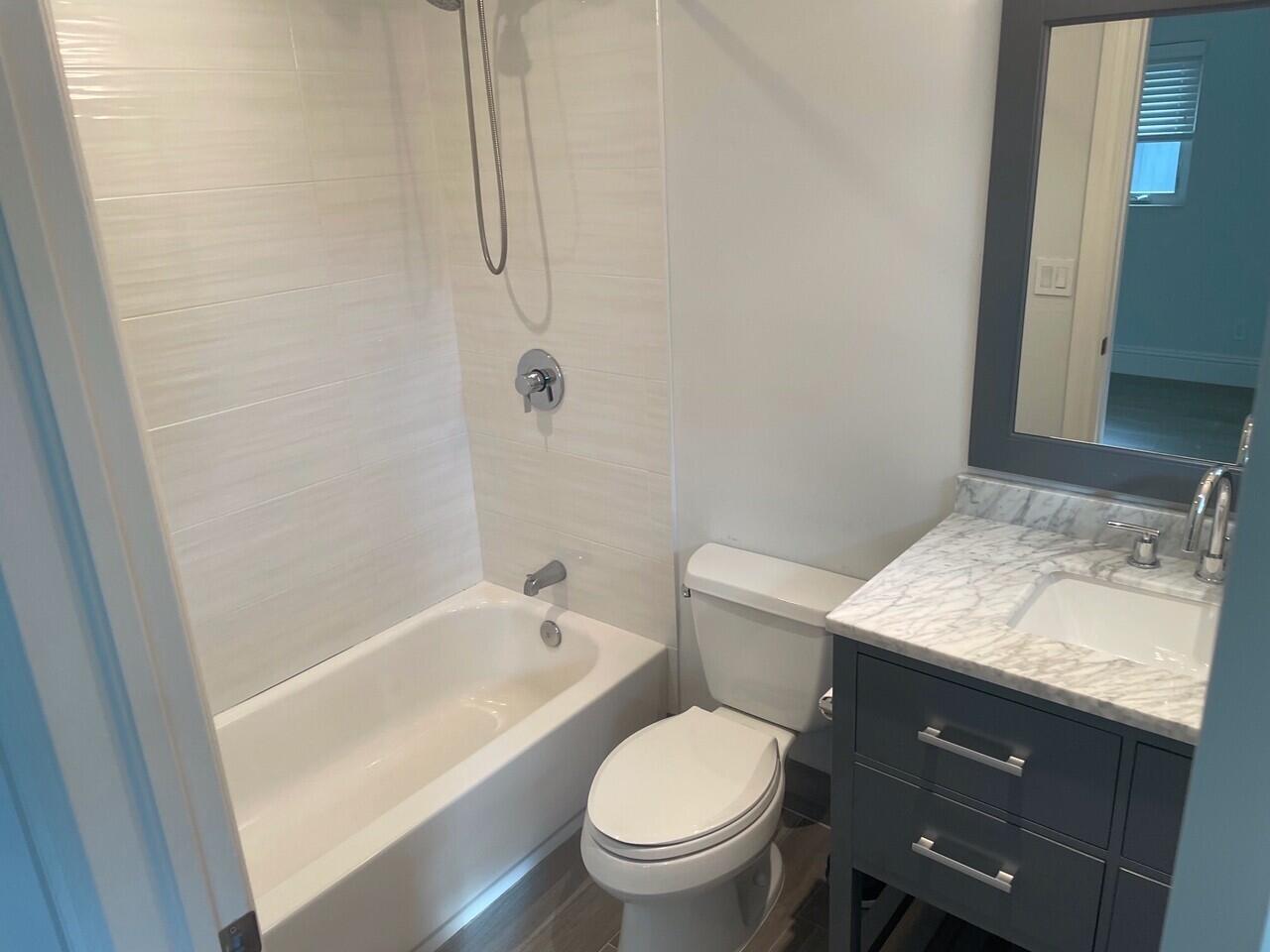 1611 Treemont Avenue Jupiter, FL 33469 - Photo 19 of 28 a bathroom with a granite countertop sink toilet and shower