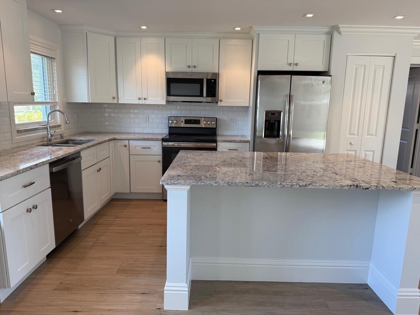 1611 Treemont Avenue Jupiter, FL 33469 - Photo 3 of 28 a kitchen with kitchen island granite countertop a stove sink and refrigerator