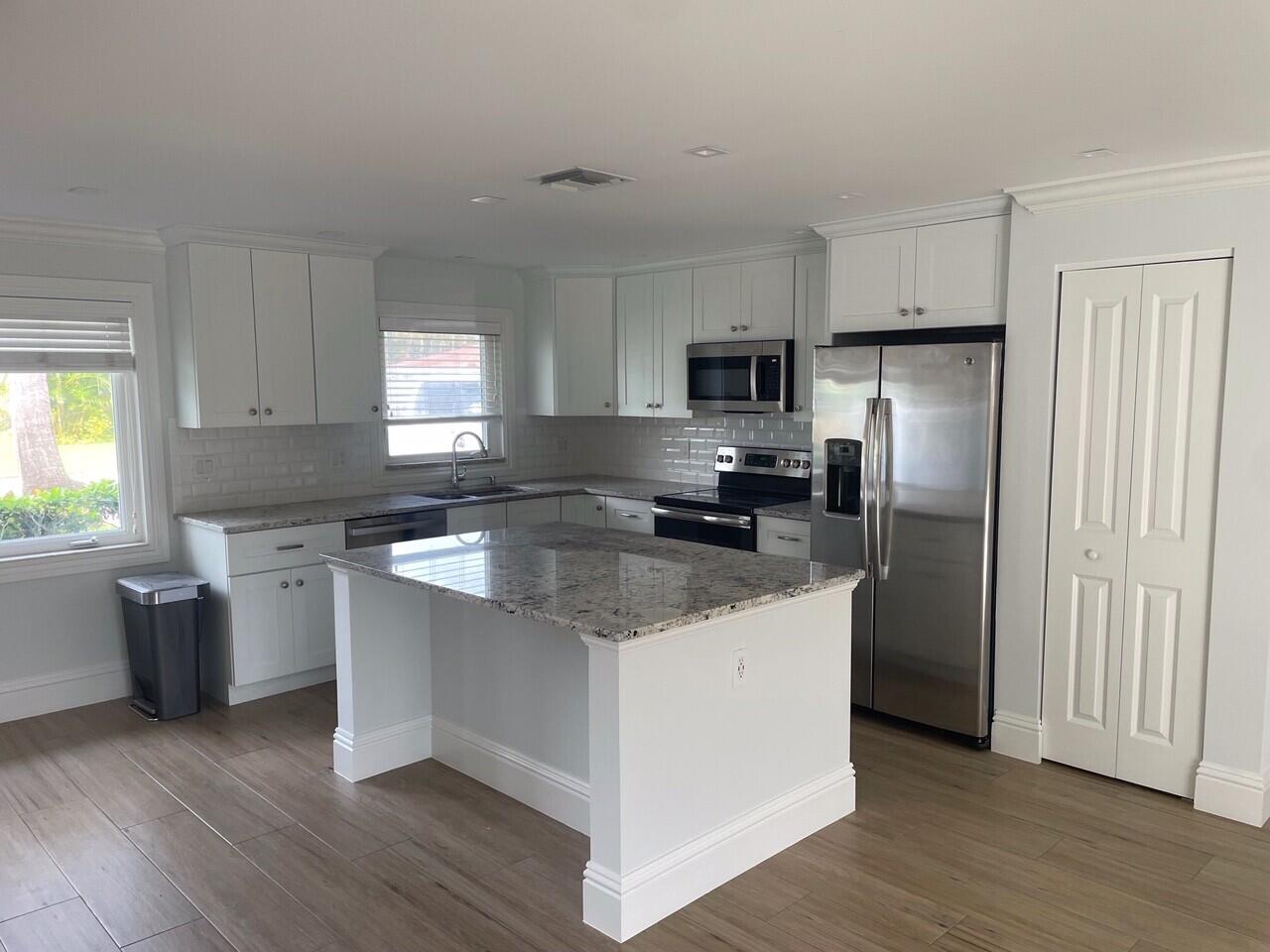 1611 Treemont Avenue Jupiter, FL 33469 - Photo 6 of 28 a kitchen with stainless steel appliances granite countertop a refrigerator a sink a stove a microwave and wooden floors