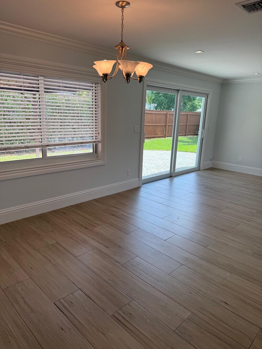 1611 Treemont Avenue Jupiter, FL 33469 - Photo 7 of 28 a view of an empty room with wooden floor and a window