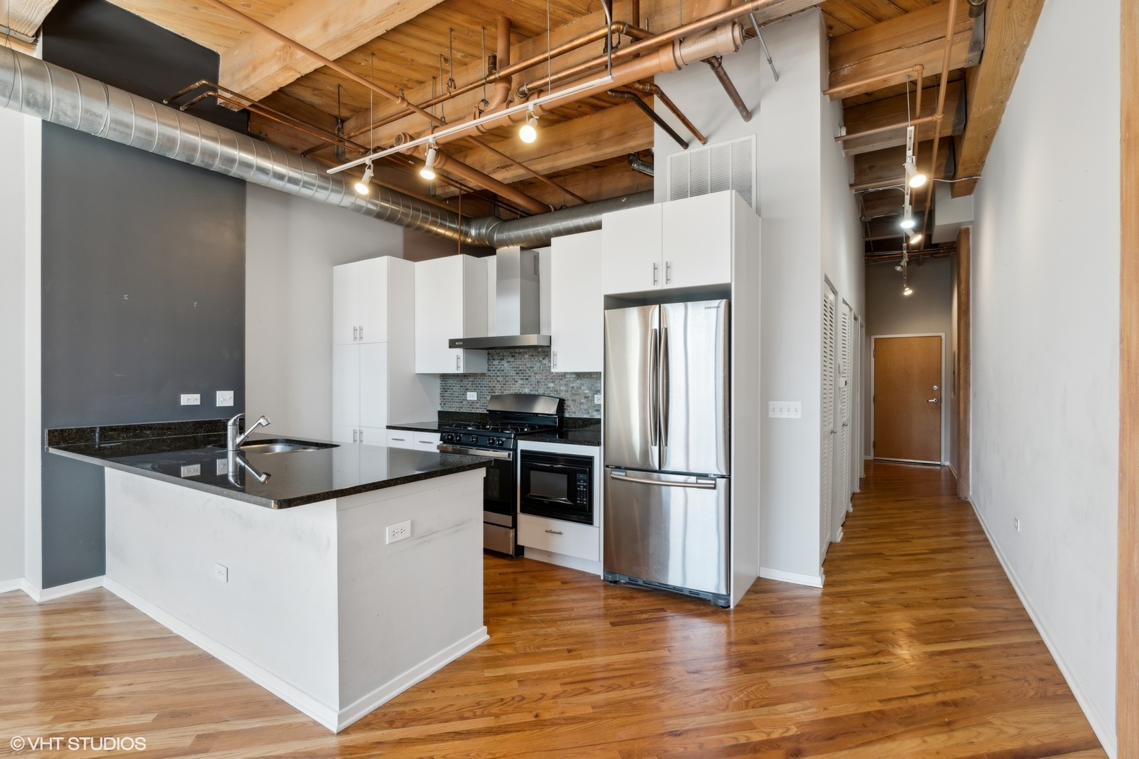 1040 West Adams Street, Unit 107 Chicago, IL 60607 - Photo 7 of 14 a kitchen with granite countertop a refrigerator and wooden cabinets
