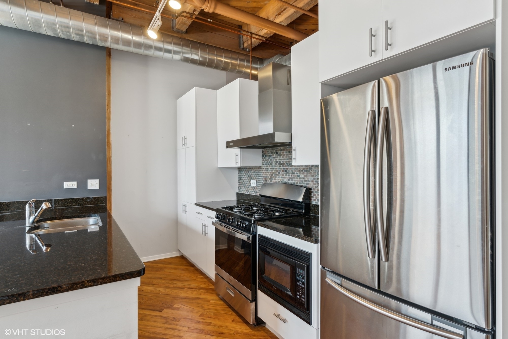 1040 West Adams Street, Unit 107 Chicago, IL 60607 - Photo 8 of 14 a kitchen with granite countertop a refrigerator and a sink