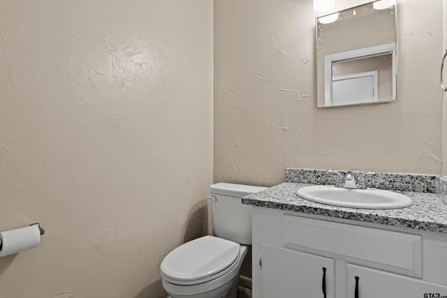 a bathroom with a granite countertop toilet and a sink