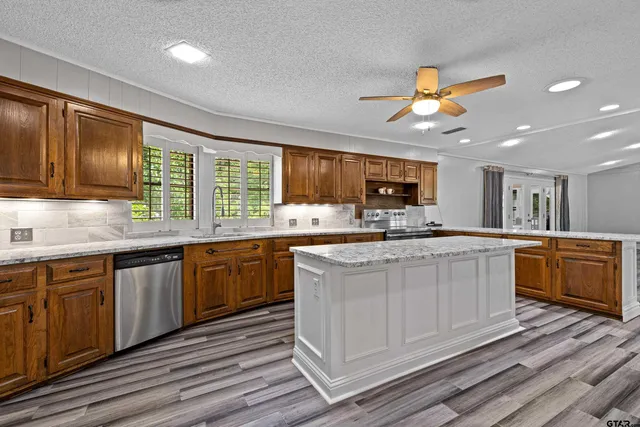 a kitchen with stainless steel appliances granite countertop wooden cabinets a sink and dishwasher a stove with wooden floor