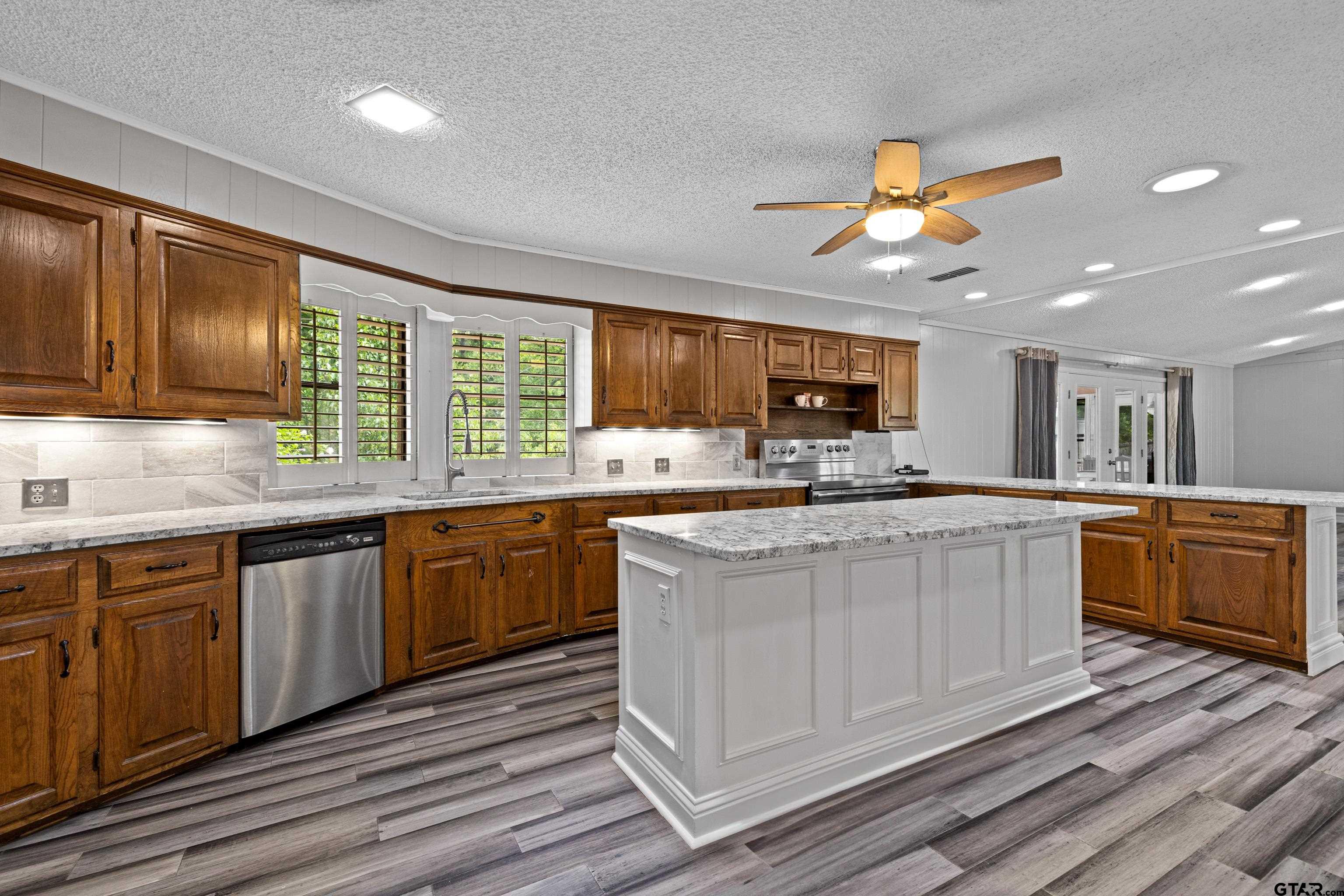 1821 Azalea Street Gilmer, TX 75644 - Photo 6 of 35 a kitchen with stainless steel appliances granite countertop wooden cabinets a sink and dishwasher a stove with wooden floor