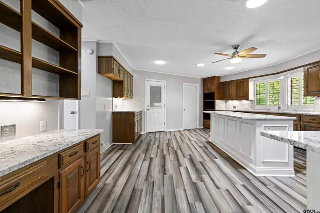a kitchen with stainless steel appliances granite countertop a lot of counter space and wooden floors