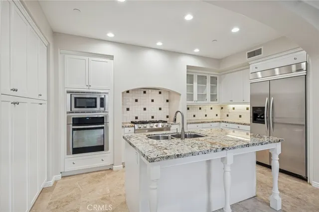 a kitchen with stainless steel appliances granite countertop a refrigerator and a stove top oven