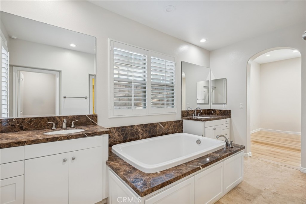22 Ridge Valley Irvine, CA 92618 - Photo 18 of 37 a bathroom with a granite countertop sink a mirror a bathtub and next to a window