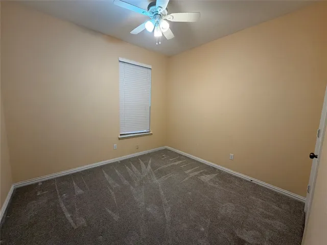 an empty room with a chandelier fan and windows