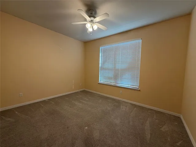 an empty room with a window and a ceiling fan
