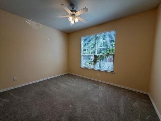 an empty room with windows and fan