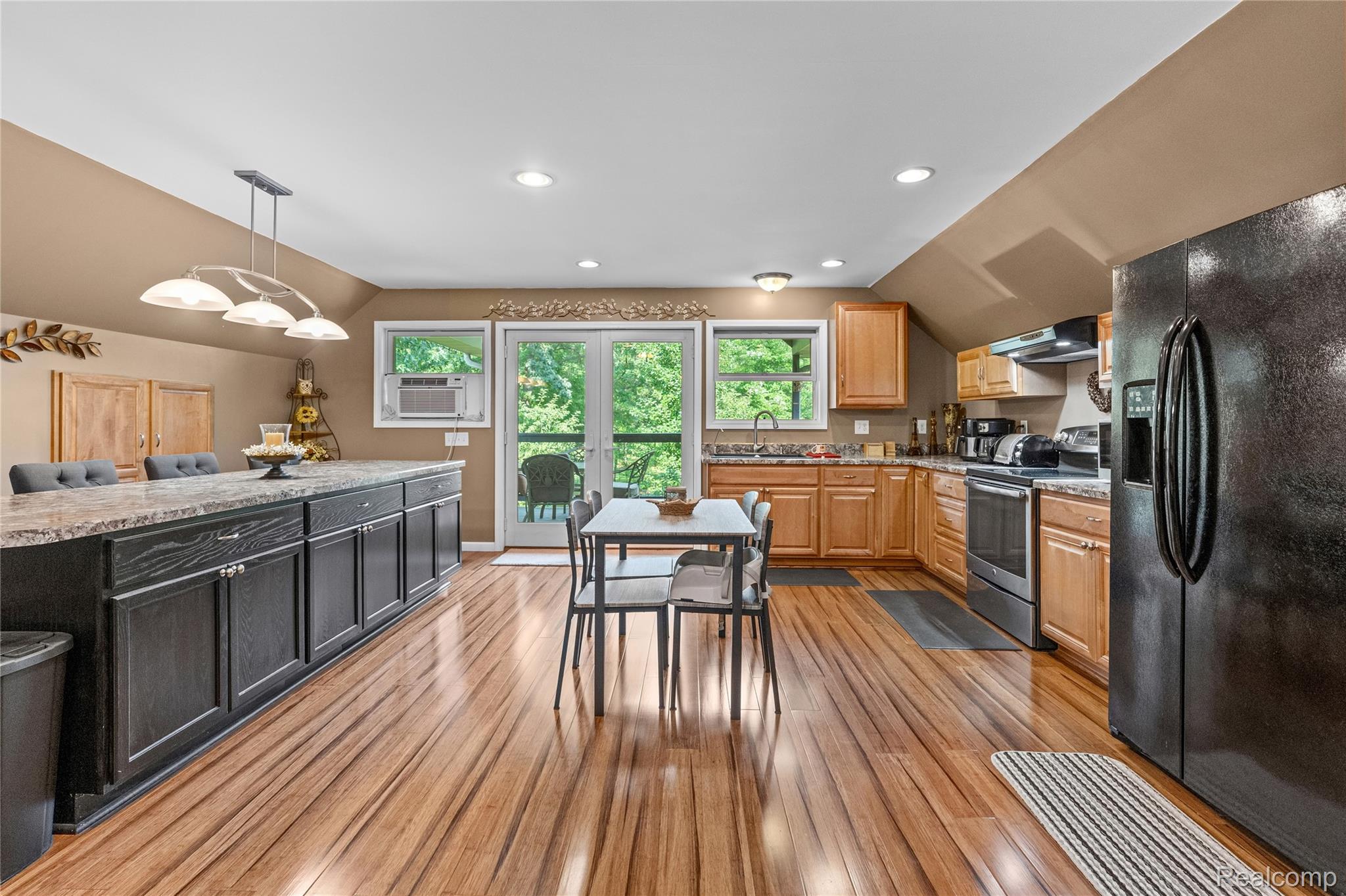 15055 South Duffield Road Byron, MI 48418 - Photo 3 of 61 Expansive kitchen featuring wood-finish flooring, a large central island with dark cabinetry, light wood-tone perimeter cabinetry, a stainless steel range, and double glass-paneled doors opening to the exterior