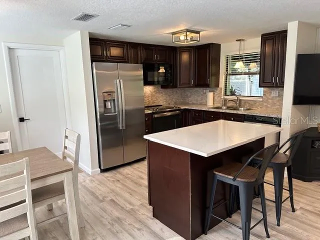 a kitchen with stainless steel appliances a table chairs refrigerator and microwave