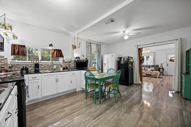 a kitchen with stainless steel appliances granite countertop a stove a refrigerator a kitchen island a dining table and chairs with wooden floor