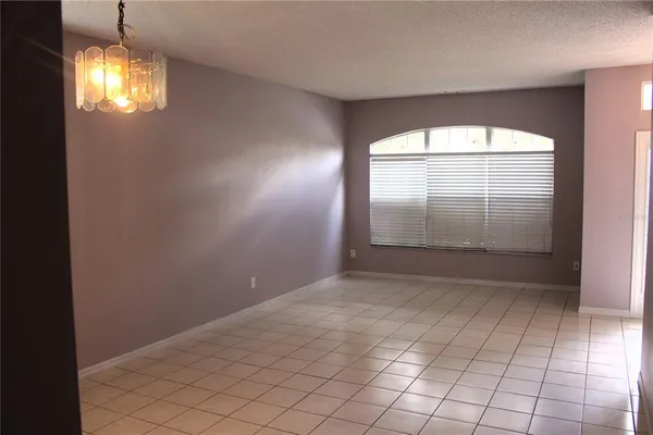 an empty room with windows and chandelier fan