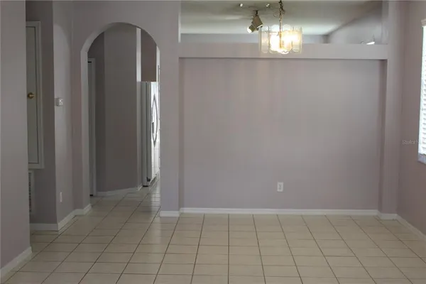 a view of empty room with wooden floor and chandelier