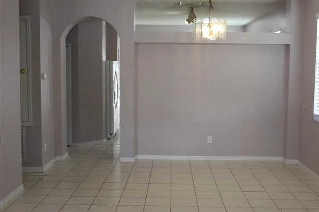 a view of empty room with wooden floor and chandelier
