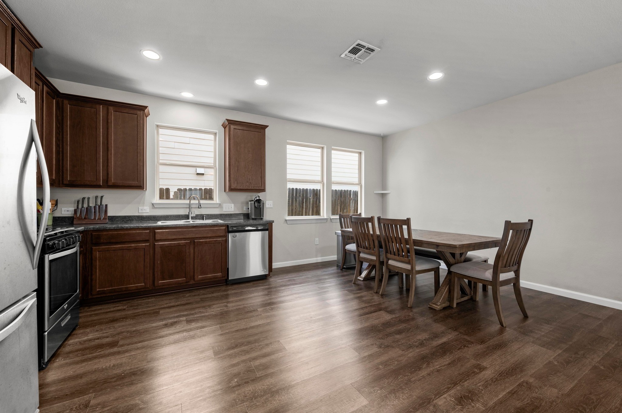 328 Triumph Road Buda, TX 78610 - Photo 8 of 18 Kitchen with appliances with stainless steel finishes, a sink, dark countertops, baseboards, and dark wood-style floors