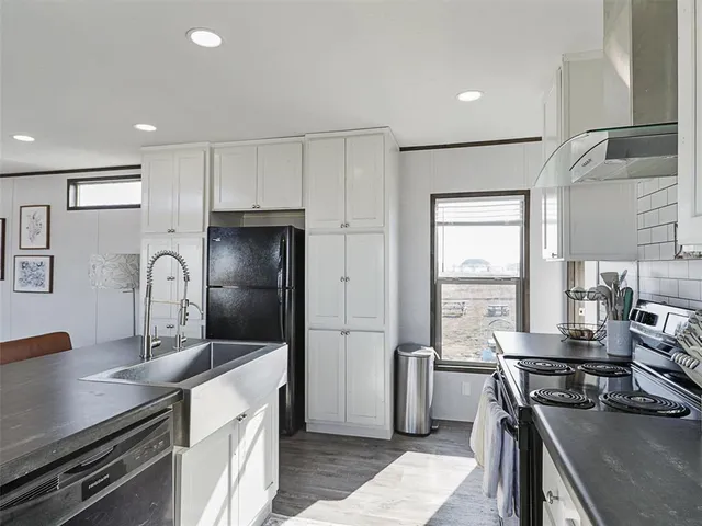 a kitchen with granite countertop a stove a sink and a refrigerator