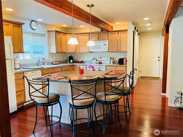 a dining area with stainless steel appliances a table and chairs with wooden floor