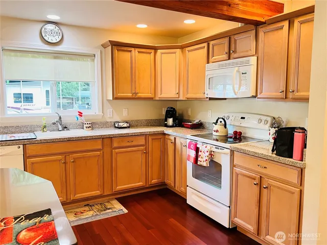 a kitchen with stainless steel appliances granite countertop a sink dishwasher stove and cabinets with wooden floor