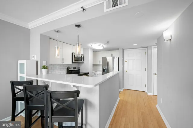 a kitchen with stainless steel appliances a dining table chairs and white cabinets