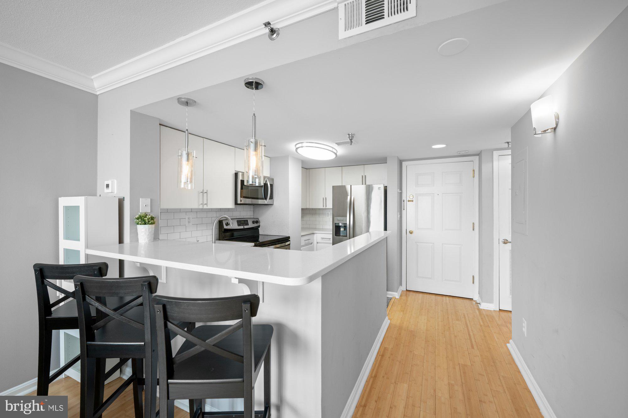 701 Pennsylvania Avenue Northwest, Unit PH2 Washington, DC 20004 - Photo 5 of 19 a kitchen with stainless steel appliances a dining table chairs and white cabinets